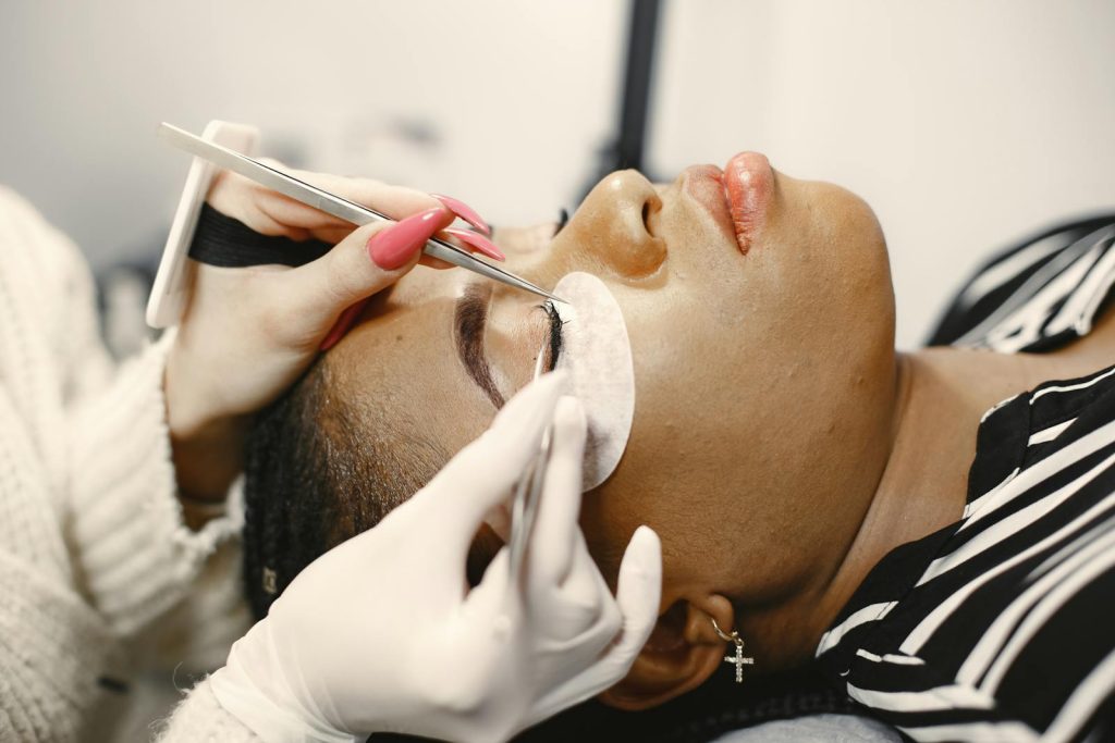 A close-up view of a woman receiving an eyelash extension treatment in a beauty salon.
